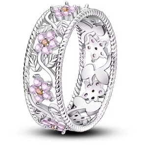 Op de afbeelding: Een zilveren ring met een delicaat bloemenontwerp met roze en oranje edelstenen. De ring heeft een gedraaide touwband en ingewikkelde uitsnijdingen.