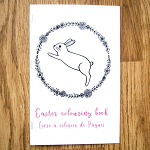 May include: Black and white coloring book cover featuring a bunny rabbit jumping through a wreath of flowers. The text "Easter coloring book" and "Livre &agrave; colorier de P&acirc;ques" is printed on the cover.