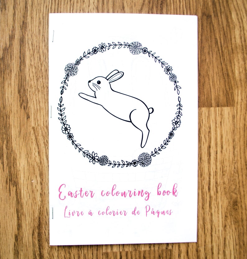 May include: Black and white coloring book cover featuring a bunny rabbit jumping through a wreath of flowers. The text "Easter coloring book" and "Livre &agrave; colorier de P&acirc;ques" is printed on the cover.