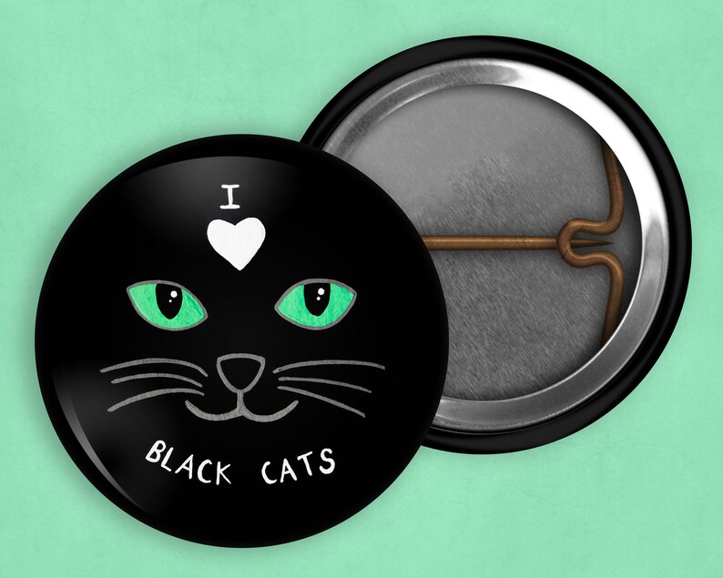 May include: A black button with a white heart and the text "I love black cats" in white. The button features a black cat with green eyes and a white nose.