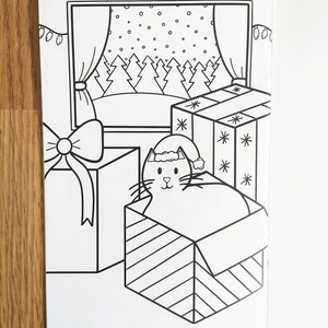 May include: A black and white illustration of a cat wearing a Santa hat inside a striped box. The cat is looking out of the box. There is a window behind the cat with a snowy scene outside. There are two wrapped presents in the image.