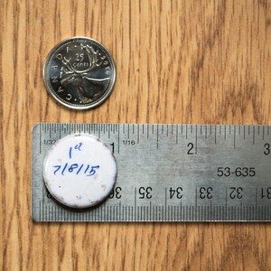 May include: A white round sticker with the text "1 1/2 7/8/15" written in blue ink. The sticker is placed on a silver ruler with markings in inches.