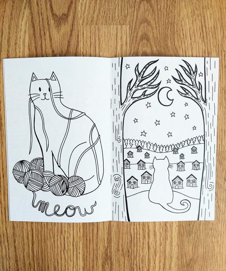 May include: A black and white coloring book page featuring a cat tangled in yarn balls with the word "meow" written below. The second page shows a cat looking out a window at a row of houses under a crescent moon and stars.