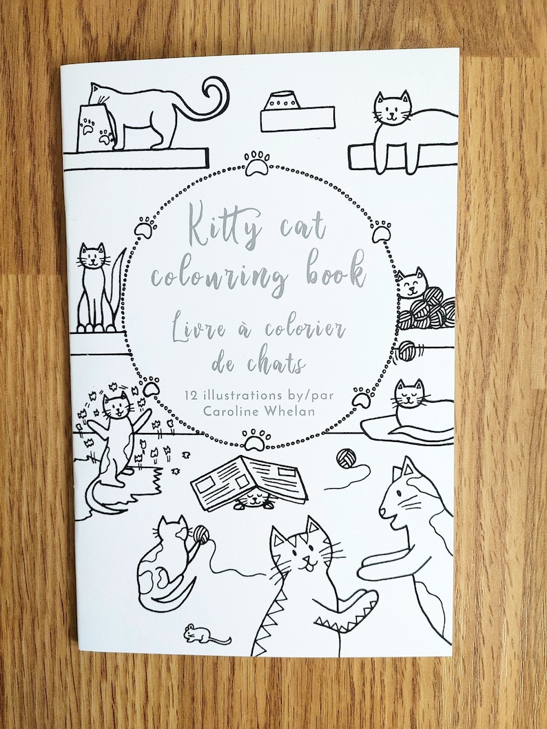 A colouring book cover with the text "KittyCat Colouringbook." It features a black and white illustration of a group of cats, playing with yarn and toys. The illustration was drawn by Caroline Whelan.