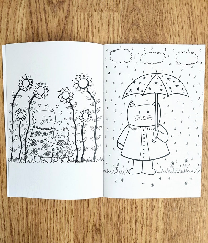 May include: A black and white coloring book page with two cats. One cat is holding an umbrella with stars on it and is standing in the rain. The other cat is standing in a field of flowers.