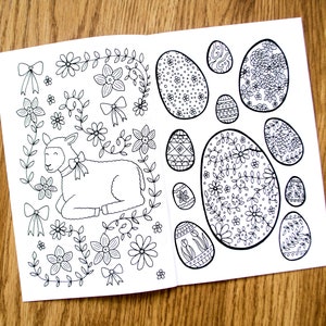May include: A black and white coloring page featuring a lamb surrounded by flowers and a variety of eggs with intricate designs.