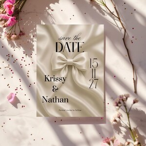 May include: A wedding invitation with the text "save the DATE" and the names "Krissy & Nathan". The date "15/11/27" is displayed. The design features a satin bow and a soft, neutral color palette.