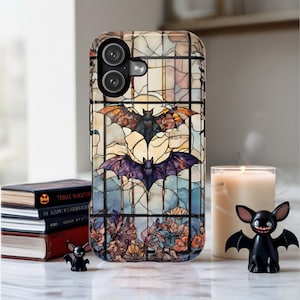 May include: A phone case with a stained-glass design featuring bats and floral elements. The case has a black camera module and a glossy finish. The design includes bats in shades of orange, purple, and black against a backdrop of blue and yellow.