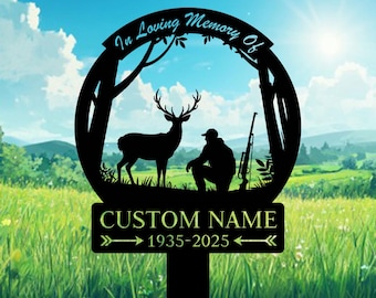 May include: Black metal memorial stake featuring a deer, hunter, and rifle silhouette within a circular frame. The text "In Loving Memory Of" arches above the scene. Below, a sign reads "CUSTOM NAME" and "1935-2025" with arrows.