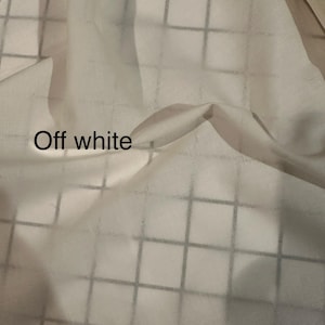 May include: Off-white fabric with a grid pattern. The fabric is draped, creating soft folds and shadows. The text "Off white" is visible in the lower left corner.