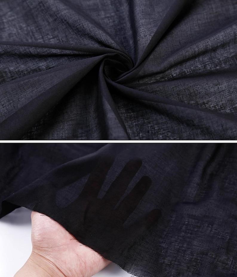 May include: Close-up of a dark navy blue sheer fabric. The fabric is lightweight and appears to be woven with a subtle texture. The fabric is draped and folded, creating shadows and depth. The fabric is held up to the light, revealing the hand behind it.