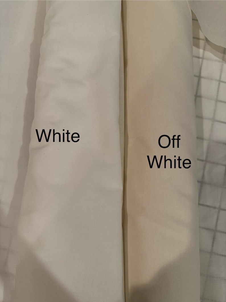 May include: Two fabric rolls, one labeled "White" and the other "Off White." The white fabric is a bright, clean shade, while the off-white has a warmer, creamier tone. The fabrics are tightly rolled, showing their texture.