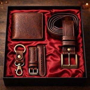 May include: A brown leather gift set presented in a black box with a red satin lining. The set includes a wallet, belt, watch straps, and a keychain. The belt has a gold-colored buckle. The leather items have a textured appearance.