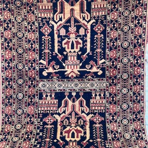 Könnte beinhalten: Rechteckiger Teppich mit einem komplizierten geometrischen Design. Der Teppich hat ein dunkelblaues Mittelfeld mit beigen und burgunderfarbenen Mustern. Der Rand ist ein sich wiederholendes Muster aus burgunderfarbenen und beigen Formen.