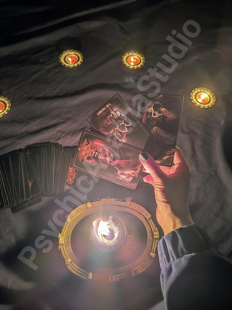 May include: A dimly lit scene featuring tarot cards, lit candles, and a decorative candle holder. The cards are held above a lit candle, with other candles scattered around. The text "Psychic AzaStudio" is visible.