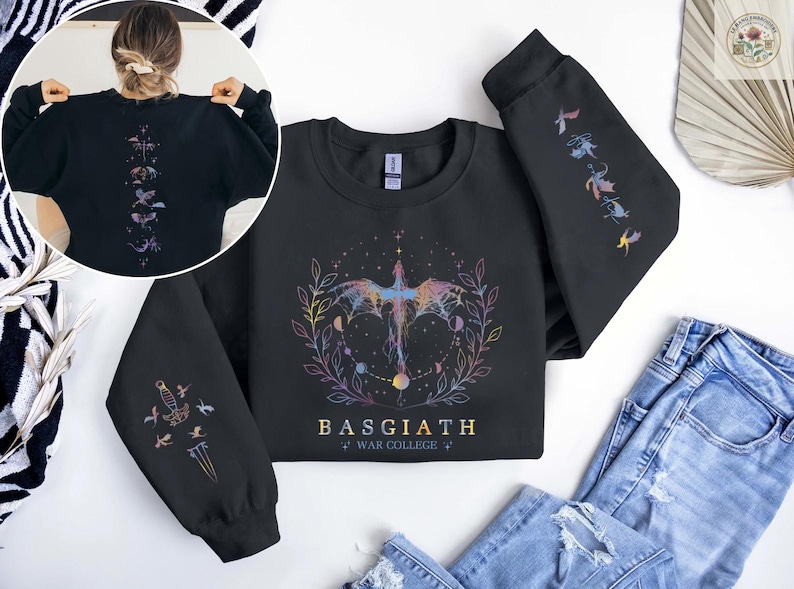 May include: Black sweatshirt with a colorful dragon design, the text "BASGIATH WAR COLLEGE", and illustrations on the sleeves. The back of the sweatshirt has a vertical design of celestial elements.