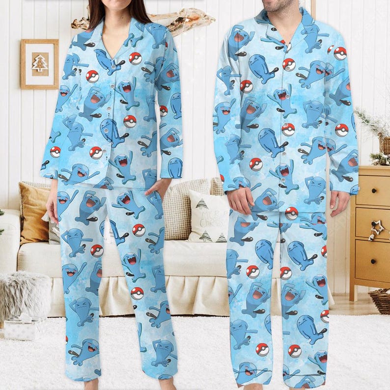 Puede incluir: Conjunto de pijama azul claro con un patr&oacute;n repetido de personajes de dibujos animados azules y bolas rojas y blancas. La parte superior de manga larga tiene una parte delantera abotonada y los pantalones tienen un ajuste relajado. El pijama est&aacute; hecho de un material suave y c&oacute;modo.