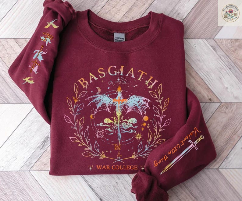 Peut inclure: Sweat-shirt bordeaux avec un motif graphique repr&eacute;sentant une &eacute;p&eacute;e, un dragon et le texte "BASGIATH WAR COLLEGE". Les manches comportent des illustrations suppl&eacute;mentaires et les mots "Violent little thing".
