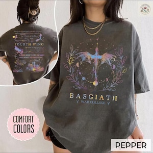 May include: Dark grey t-shirt with a colourful dragon graphic and the text "BASGIATH WAR COLLEGE". The back of the shirt features text and the words "FOURTH WING". The shirt is labelled "PEPPER" and "COMFORT COLORS".