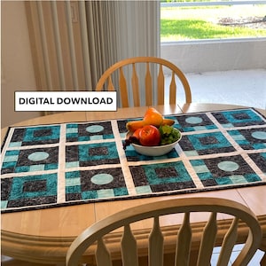 May include: A table runner with a geometric pattern in black, white and teal. The runner is laid on a wooden table with two chairs. A bowl of fruit sits on the table runner.