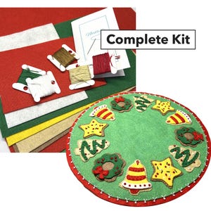 May include: A complete kit for a felt Christmas tree ornament craft project. The kit includes felt pieces in various colors, embroidery floss, and instructions. The ornament features a green felt circle with a red felt border, and is decorated with felt gingerbread cookies, bells, and wreaths.