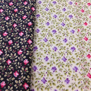 May include: Three strips of fabric featuring a repeating floral pattern. The left strip is black with pink flowers and green leaves. The middle strip is off-white with purple flowers and green leaves. The right strip is off-white with pink flowers.