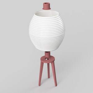 May include: A modern, white, spherical lamp with a ribbed design, supported by a three-legged, dusty rose base. The lamp has a matching dusty rose top. The lamp is a decorative lighting fixture.