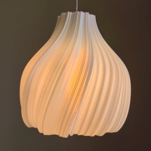 May include: A white pendant light with a distinctive, swirling pattern. The light fitting has a rounded shape with a series of curved, vertical ridges. The interior glows with a warm, soft light, creating a modern and elegant aesthetic.