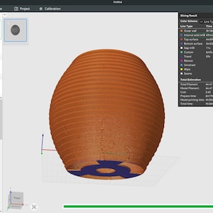 May include: A 3D model of a brown, ribbed, egg-shaped object with a blue base, displayed on a computer screen. The screen shows slicing software settings, including layer height and line width. The object is likely for 3D printing.