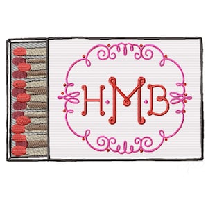 May include: Embroidered matchbox design with a white background. The matchbox features a pink decorative frame with the letters "HMB" in red. The match heads are red, and the match sticks are brown and beige.