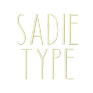 May include: Cream-colored text on a white background spells out "SADIE TYPE" in a minimalist, sans-serif font. The letters are tall and slender, with a clean, modern aesthetic. The design is simple and elegant.
