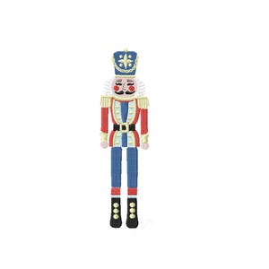 May include: A colorful, embroidered nutcracker figurine. The figurine features a blue and gold crown, a red jacket with gold trim, blue pants, and black boots. The nutcracker has a white mustache and hair.