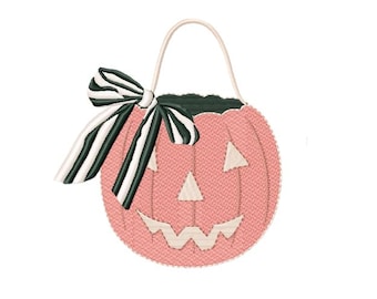 May include: A pink pumpkin-shaped bucket with a textured surface, featuring a carved face with cream-colored eyes, nose, and mouth. A large bow with black and white vertical stripes is attached to the side, and a thin handle is at the top.