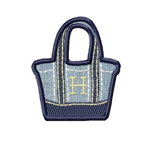 May include: Embroidered denim tote bag patch with a navy blue border and handle. The bag features vertical stripes and a gold-coloured letter "H" in the centre. The denim has a light blue wash.