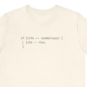 Puede incluir: Camiseta color crema con texto negro. El texto dice: "if (life == tooSerious) { | life = -fun; }" en formato de código. La camiseta tiene cuello redondo y mangas cortas.