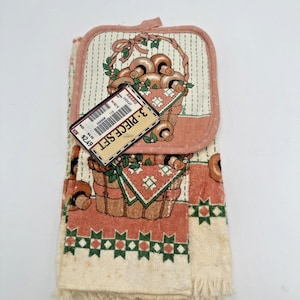 Può includere: Un set da cucina da 3 pezzi con una presina e un asciugamano con un design a cestino di funghi. La presina e l'asciugamano hanno uno sfondo color crema con un motivo ripetuto di funghi e accenti verdi. L'asciugamano ha un bordo sfrangiato.