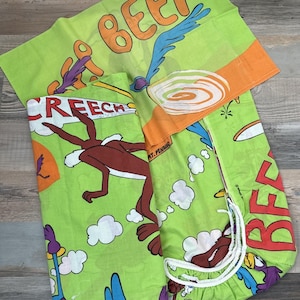 May include: Bright green bedding set featuring cartoon characters. The set includes a pillowcase and a fitted sheet with images of the Road Runner and Wile E. Coyote. The pillowcase has the word "BEEP" in orange letters. The fitted sheet has the word "CREEECH" in red letters.