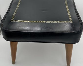 Taburete/asiento cuadrado de vinilo negro estilo era atómica MCM con detalles dorados.