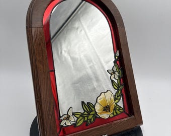 Estilo vintage de los años 80: espejo arqueado con borde de madera y decoración floral de imitación vidriera.