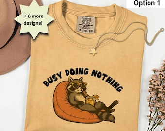 Camiseta "Busy Doing Nothing" - Colores cómodos - Camiseta de mapache - Diseño divertido de animal perezoso - 7 diseños