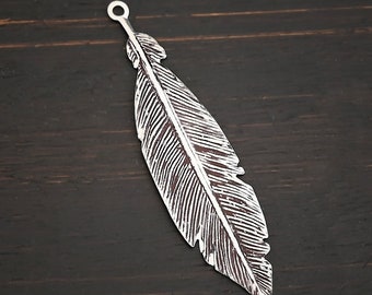 Op de afbeelding: Een zilveren veerbedel met een gedetailleerd ontwerp. De bedel heeft een lus aan de bovenkant om aan sieraden te bevestigen.