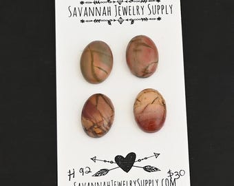 May include: Four oval-shaped, red, brown, and white patterned agate cabochons on a white card with the text "Savannah Jewelry Supply" and "SavannahJewelrySupply.com".