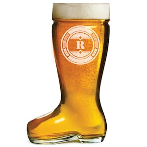 May include: A clear glass boot-shaped beer stein with a white foam head. The stein has a white circle design with a black letter "R" in the center.