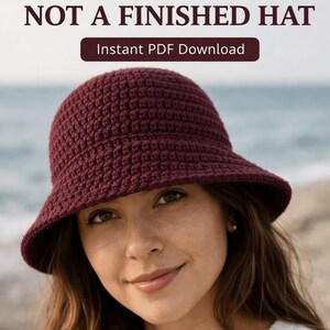 May include: A burgundy crochet bucket hat. The image includes the text "BEGINNER CROCHET PATTERN NOT A FINISHED HAT" and "Instant PDF Download". The hat is worn by a person with long brown hair.