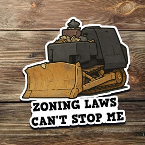 May include: A yellow and black bulldozer cartoon sticker with the text "Zoning Laws Can't Stop Me".