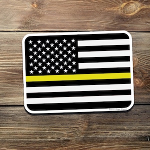 May include: Black and white American flag with a thin yellow stripe across the middle. The flag has a white background with black stars in the top left corner and black stripes across the rest of the flag. The text "Denver Eagle Media" is in the bottom right corner.