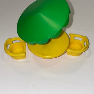 May include: A yellow plastic table and two chairs with a green umbrella. The table and chairs are designed for small children.