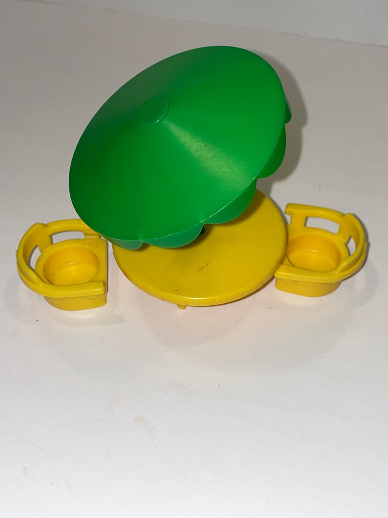 May include: A yellow plastic table and two chairs with a green umbrella. The table and chairs are designed for small children.