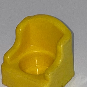 May include: A yellow plastic toy potty chair for children. The chair has a rounded seat and a back.