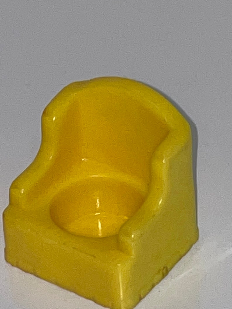 May include: A yellow plastic toy potty chair for children. The chair has a rounded seat and a back.